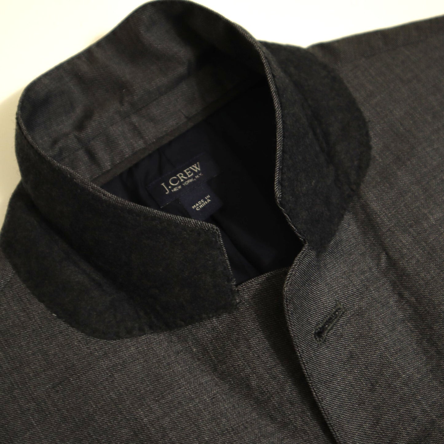 Close-up of a gray suit jacket with 'J.Crew' label on a white background