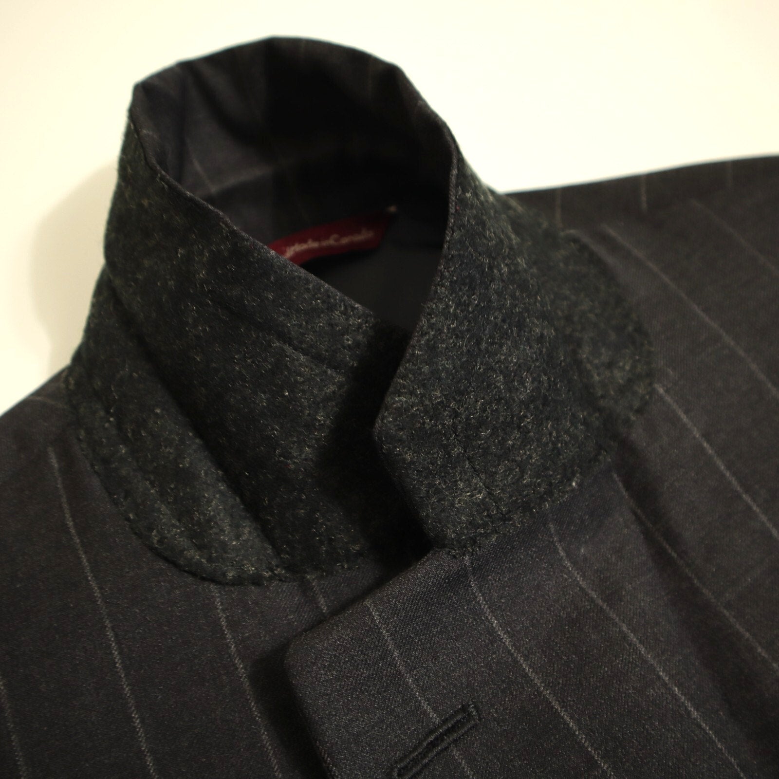 Close-up of a dark gray pinstripe suit with a textured collar on a light background